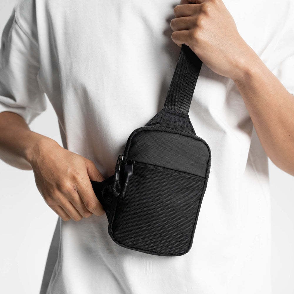 Compact black crossbody sling bag worn across the front of the body