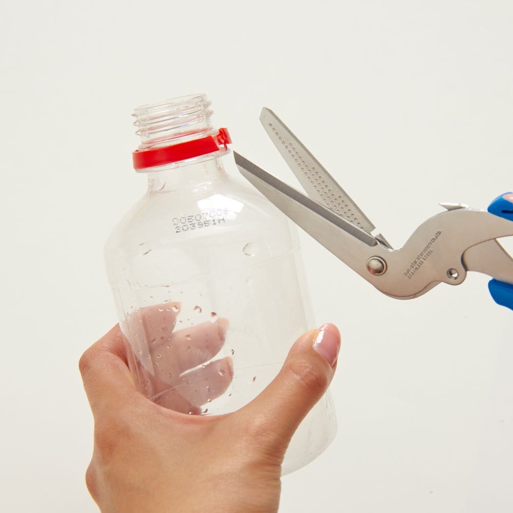Scissors removing plastic tamper ring from bottle neck