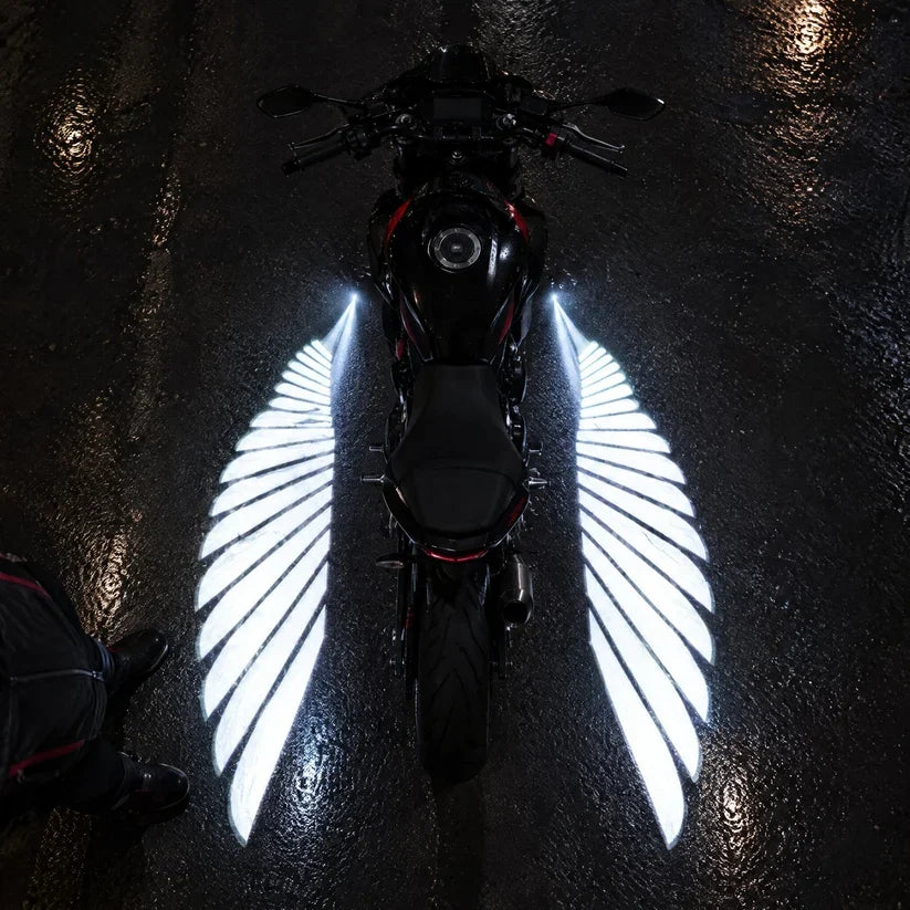 Overhead view of a motorcycle with symmetrical white angel wing light projections spreading across the pavement
