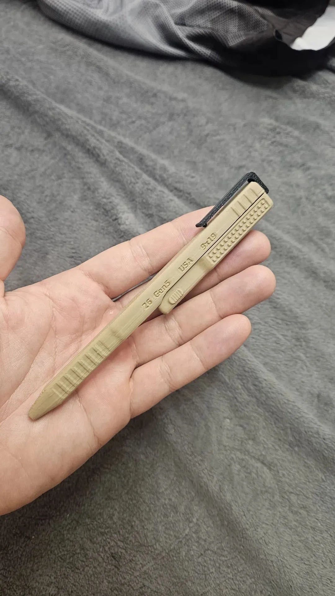 Khaki slide-action novelty ballpoint pen held in hand