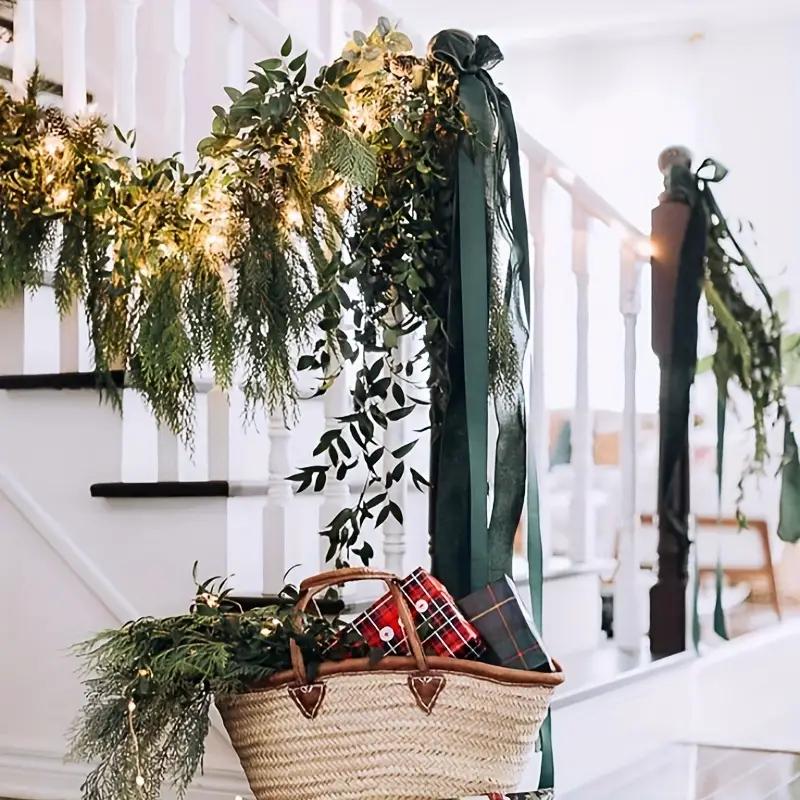 Layered artificial greenery styled with warm lights and ribbon on staircase