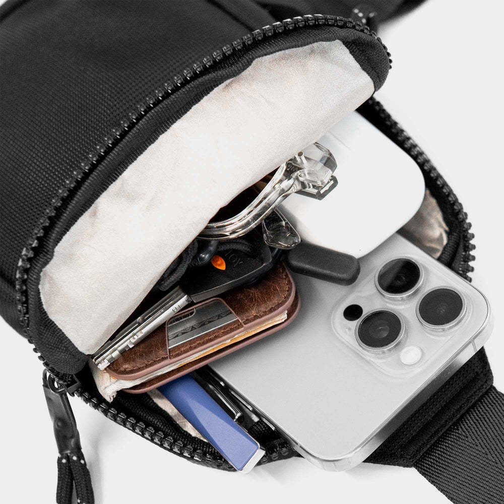 Compact sling bag holding phone wallet glasses keys and power bank