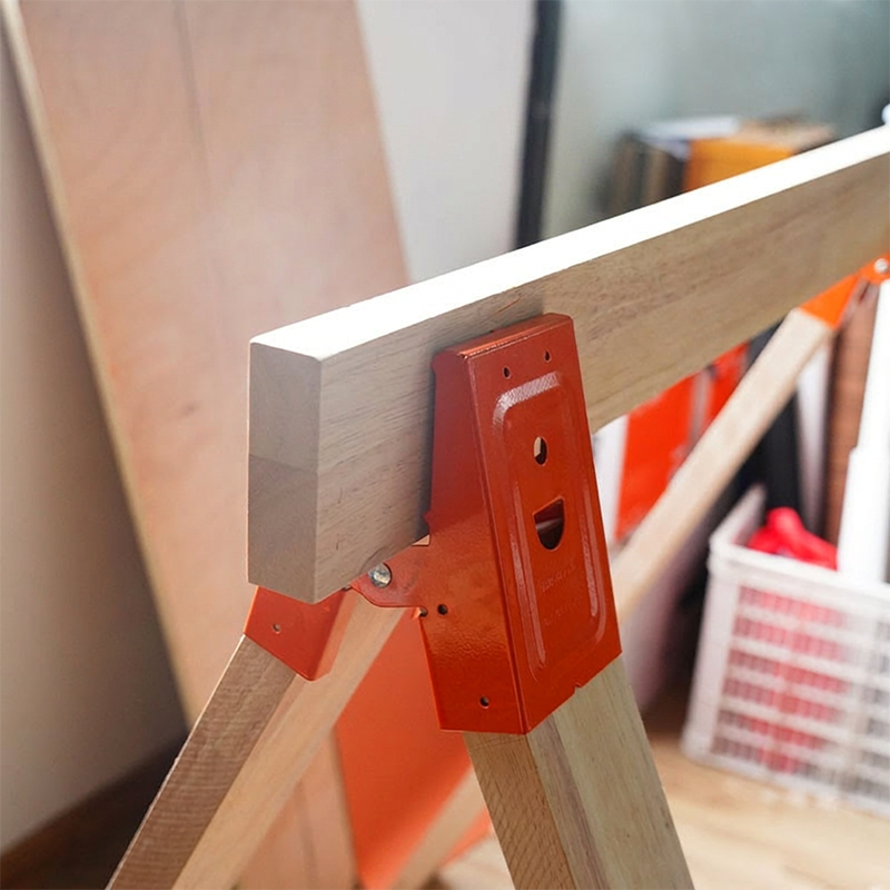 Orange steel sawhorse bracket gripping top wood rail